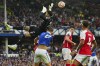 Arsenal's goalkeeper David Raya, top, blocks Everton's James Tarkowski's shot during the English Premier League soccer match between Everton and Arsenal at the Goodison Park stadium in Liverpool, England, Sunday, Sept. 17, 2023. (AP Photo/Jon Super)