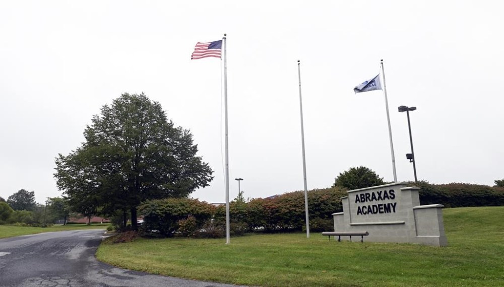 Flags flutter in the wind near an entrance to the Abraxas Academy Monday, Sept. 18 2023 in Morgantown, Pa. Nine teenagers who escaped from a detention center in Pennsylvania after overpowering staff and crawling under a fence were captured less than 12 hours later, state police said. (Bill Uhrich/Reading Eagle via AP)
