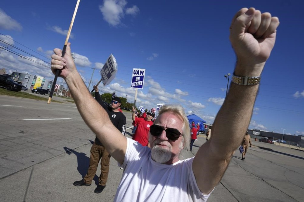 United Auto Workers member Steve Zifko raises his hands to passing traffic while walking the picket line at the Ford Michigan Assembly Plant in Wayne, Mich., Monday, Sept. 18, 2023. So far the strike is limited to about 13,000 workers at three factories — one each at GM, Ford and Stellantis. (AP Photo/Paul Sancya)
