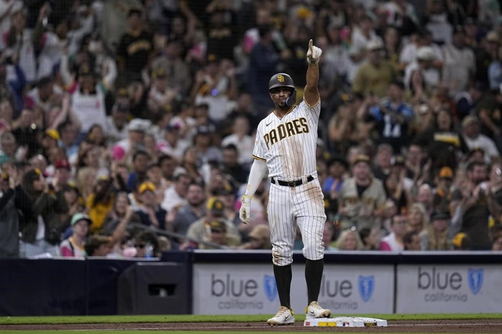 San Diego Padres' Xander Bogaerts points toward teammate Fernando Tatis Jr. after advancing from first base off an RBI single by Tatis Jr. during the fifth inning of a baseball game against the Colorado Rockies, Monday, Sept. 18, 2023, in San Diego. San Diego Padres' Eguy Rosario scored and Colorado Rockies catcher Elias Diaz picked up a throwing error on the play. (AP Photo/Gregory Bull)