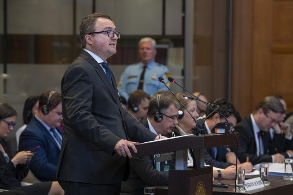 Ukraine's agent Anton Korynevych, ambassador-at-large of the Ukraine Foreign Ministry, addresses the judges at the World Court, as the Russian delegation, right, listens to Ukraine's legal battle against Russia over allegations of genocide used by Moscow to justify its 2022 invasion, which resumed in The Hague, Netherlands, Tuesday, Sept. 19, 2023. Russia seeks to have a groundbreaking case tossed out at the International Court of Justice, also known as the Word Court, in a case which will see Ukraine supported by a record 32 other nations in a major show of support for the embattled nation.(AP Photo/Peter Dejong)