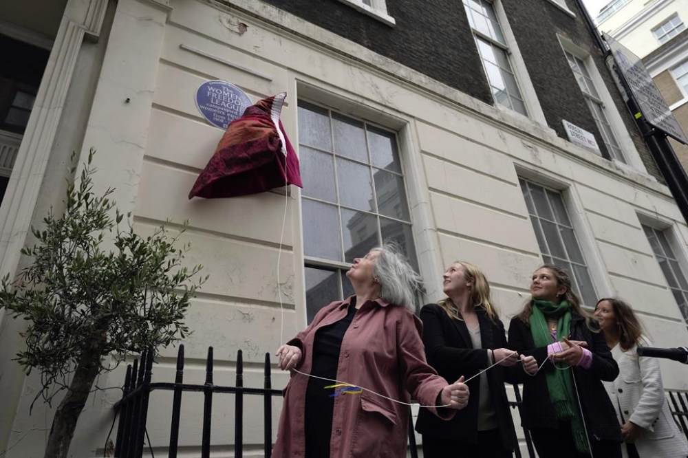 Officials unveil the plaque number 1,000 to honour the Women's Freedom League, a suffragist organisation that used 1 Robert Street in central London as its base of operations during its most active period, in London, Tuesday, Sept. 19, 2023. As English Heritage unveiled its 1,000th blue plaque on Tuesday, the charity is working to broaden the program to include more women, people from minority ethnic backgrounds and community groups so that it better reflects the diversity of the capital. (AP Photo/Kin Cheung)
