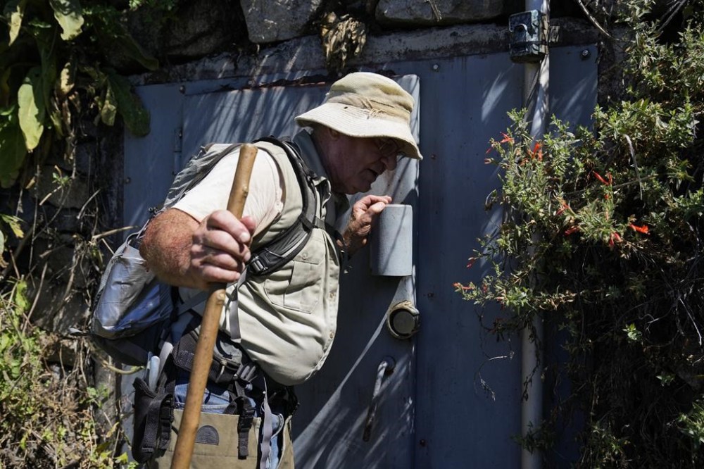 Gary Earney, retired forester with the U.S. Forrest Service, listens for the sound of water flowing through an area where BlueTriton collects spring water in the San Bernardino National Forest on Monday, Sept. 18, 2023, in San Bernardino, Calif. Earney handled water permits for springs in that area from 1978-2007. The State Water Resources Control Board is expected to vote Tuesday on whether to issue a cease-and-desist order against BlueTriton, the company that produces the widely-known Arrowhead brand of bottled water. The order would prevent BlueTriton from drawing water from certain points in the San Bernardino National Forest. (AP Photo/Ashley Landis)