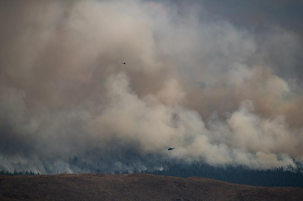 Helicopters fly past the Tremont Creek wildfire as it burns on the mountains above Ashcroft, B.C., on Friday, July 16, 2021. Proof that deer experienced elevated stress in response to blazes in British Columbia's southern Interior can be found in the animals' poop, although researchers say there's still much to learn about what wildfire means for wildlife. THE CANADIAN PRESS/Darryl Dyck