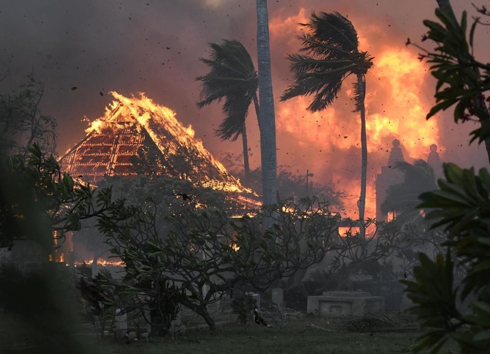 FILE - The hall of historic Waiola Church in Lahaina and nearby Lahaina Hongwanji Mission are engulfed in flames along Wainee Street on Aug. 8, 2023, in Lahaina, Hawaii. Soon after Lahaina Hongwanji Mission burned in a wildfire that decimated much of the historic coastal town, the Japanese Buddhist temple's resident minister was desperate to go back and see what remained. Now, he's more hesitant. The Rev. Ai Hironaka and other Lahaina residents are grappling with a range of feelings as Maui authorities plan to begin allowing them back into what has become known as the