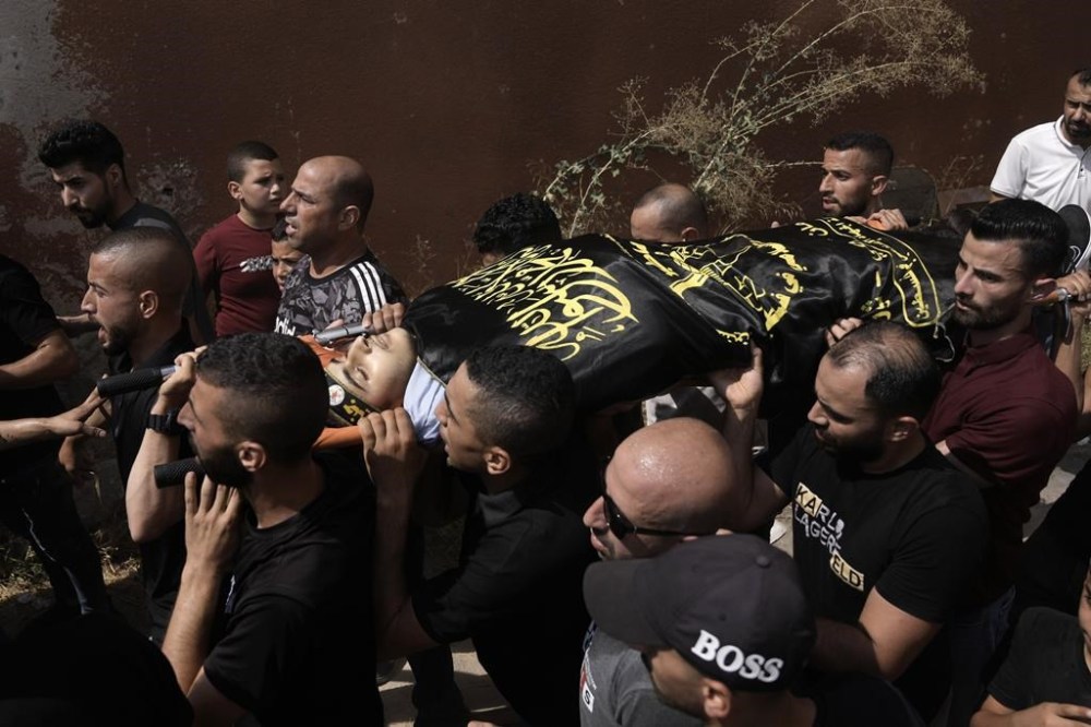 Mourners carry the body of Abdallah Abu Hasan, an 18-year-old militant Palestinian authorities said was killed by Israeli fire Friday morning, during his funeral in the village of Al-Yamoun, near the West Bank city of Jenin, Friday, Sept. 22, 2023. Hasan's body is wrapped in a Islamic Jihad flag — the group claimed Hasan as one of its militant fighters. The Israeli army said the incident occurred during a nighttime raid into the West Bank, after Palestinians fired and threw explosives at soldiers in the town of Kafr Dan. Soldiers shot back, hitting Hasan. (AP Photo/Majdi Mohammed)