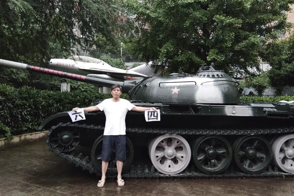 In this photo taken June 4, 2018 and released by Chen Siming, Chen Siming holds up pieces of paper with the Chinese characters for 6 and 4 referring to June 4 next to a display of an obsolete tank in Zhuzhou in central China's Hunan province. The Chinese dissident known for regularly commemorating the June 4, 1989 crackdown on pro-democracy protesters in Beijing's Tiananmen Square has fled to Taiwan and is pleading for help in seeking asylum in the United States or Canada. (Chen Siming via AP)