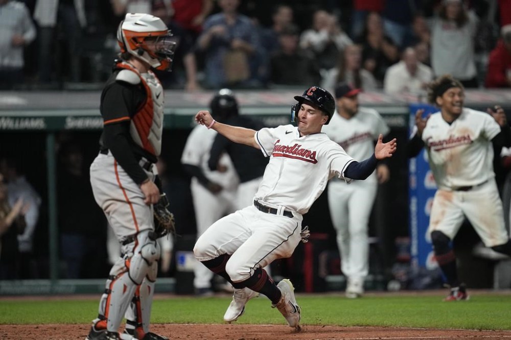 Cleveland Guardians' Will Brennan scores the winning run next to Baltimore Orioles catcher Adley Rutschman during the ninth inning of a baseball game Friday, Sept. 22, 2023, in Cleveland. (AP Photo/Sue Ogrocki)