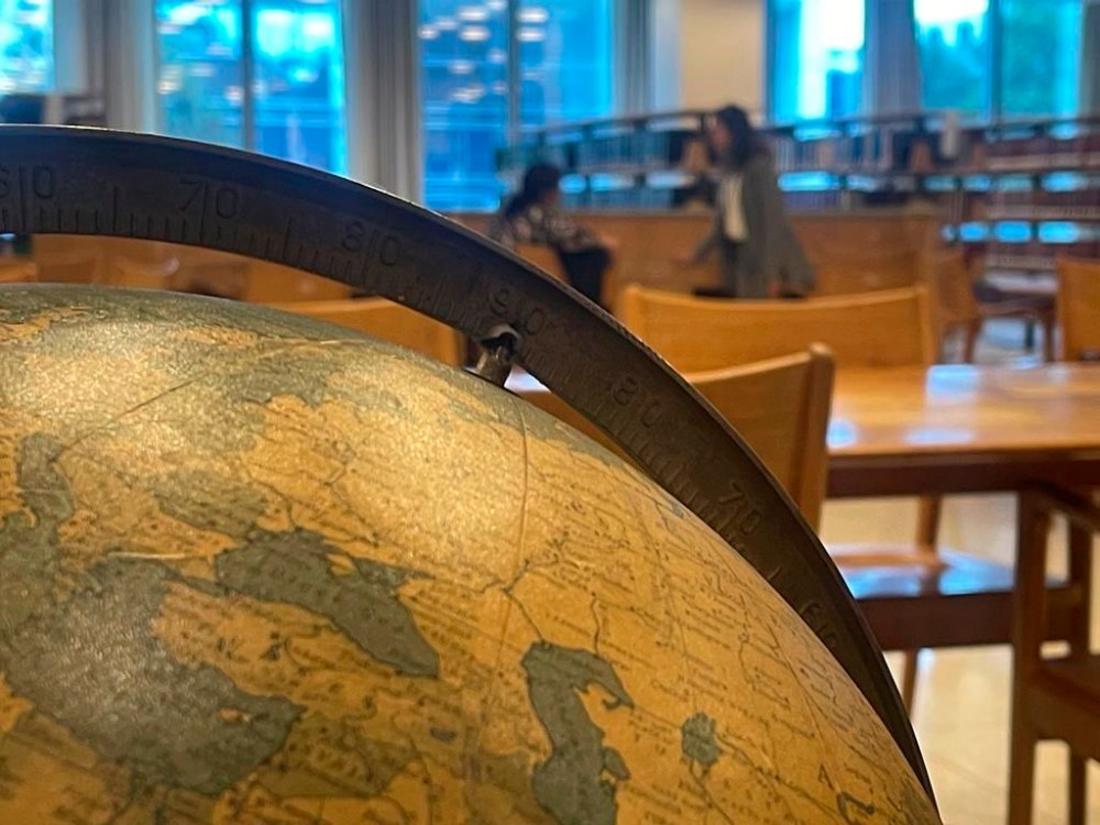 People talk quietly in the U.N. library while an old globe sits in the foreground on Friday, Sept. 22, 2023, at United Nations headquarters. The library is one of several areas in the U.N. compound where people whose job is to handle the problems and challenges of the world can relax for a few minutes. (AP Photo/Ted Anthony)