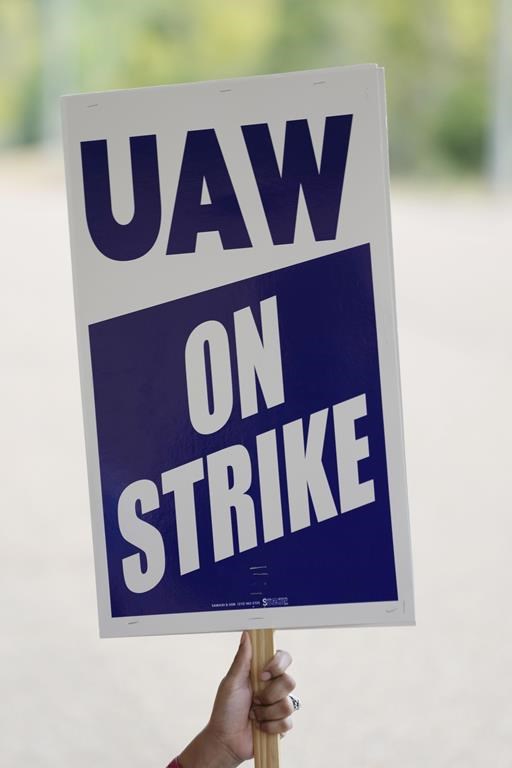 A UAW Local 2402 member waves a picket sign outside the General Motors Customer Care and Aftersales facility in Brandon, Miss., Friday, Sept. 22, 2023. The unionized workers joined others Friday in new nationwide walkouts as the labor standoff continues. (AP Photo/Rogelio V. Solis)