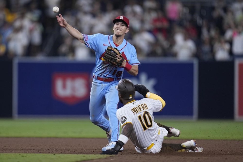 St. Louis Cardinals second baseman Tommy Edman, left, throws to first base too late for a double play as San Diego Padres' Jurickson Profar slides in late to second base during the ninth inning of a baseball game Saturday, Sept. 23, 2023, in San Diego. San Diego Padres' Eguy Rosario scored and Xander Bogaerts was safe at first on the play. (AP Photo/Gregory Bull)