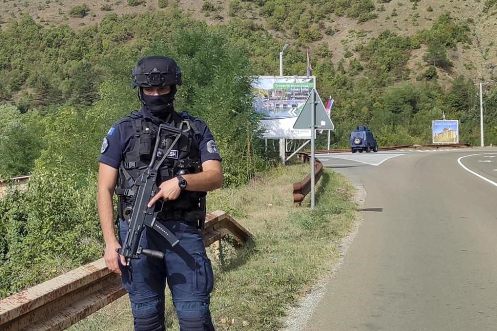 A Kosovo police officer guards the road near the village of Banjska, 55 kilometers (35 miles) north of the capital Pristina, northern Kosovo, Sunday, Sept. 24, 2023. Prime Minister Albin Kurti on Sunday said one police officer was killed and another wounded in an attack he blamed on support from neighboring Serbia, increasing tensions between the two former war foes at a delicate moment in their European Union-facilitated dialogue to normalize ties. (AP Photo/Dejan Simicevic)