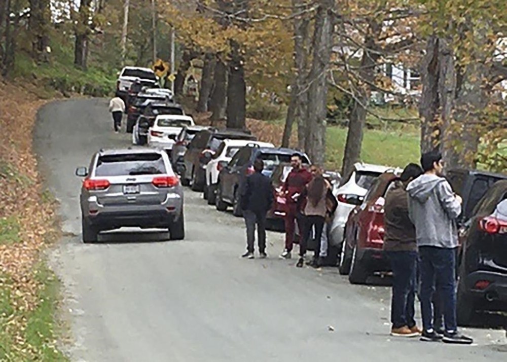 People and cars line a narrow road outside a private property in an undated photo, in Pomfret, Vt., that has become a destination for fall foliage viewers, clogging the rural road. The town is closing the road to leaf peepers through mid-October 2023 because it says the increased traffic has caused significant safety, environmental, aesthetic and quality of life issues. (AP Photo)