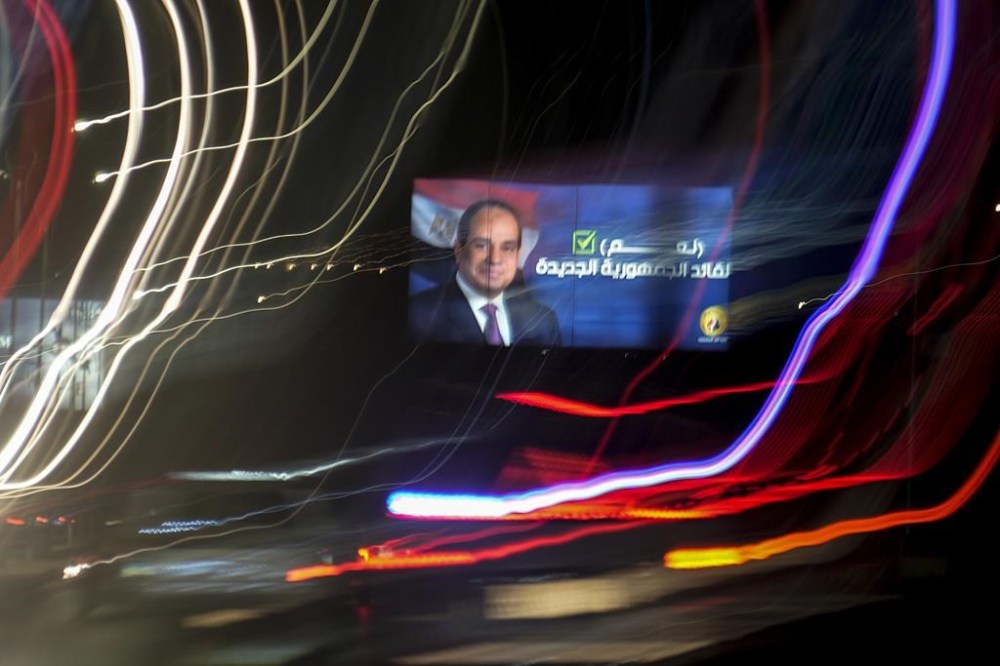 In this photo made with a slow shutter speed, vehicles pass under a billboard supporting Egyptian President Abdel Fattah el-Sissi for the coming presidential elections, in Cairo, Egypt, Monday, Sept. 25, 2023. Arabic reads