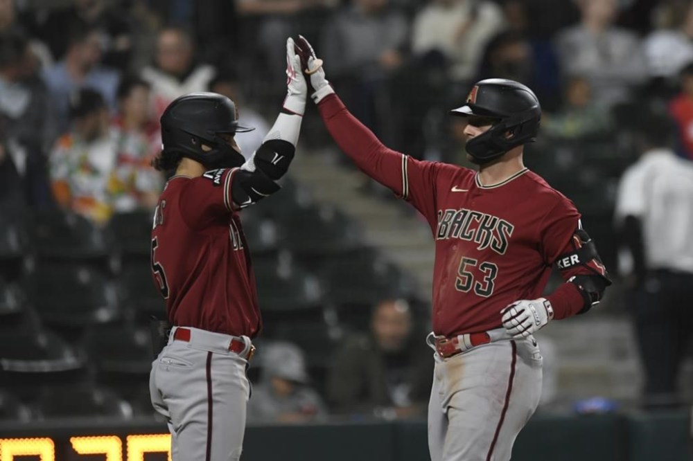 Arizona Diamondbacks' Christian Walker (53) celebrates with teammate Alek Thomas at home plate after hitting a two-run home run during the sixth inning of a baseball game against the Chicago White Sox, Tuesday, Sept. 26, 2023, in Chicago. (AP Photo/Paul Beaty)