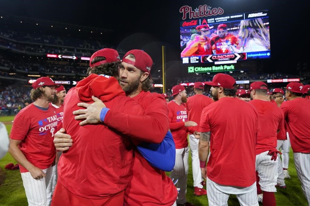 Philadelphia Phillies' Bryce Harper, right, and Rhys Hoskins celebrate after winning a baseball game against the Pittsburgh Pirates to clinch a wild-card playoff spot, Tuesday, Sept. 26, 2023, in Philadelphia. (AP Photo/Matt Slocum)
