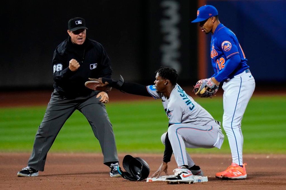 Miami Marlins' Jazz Chisholm Jr., center, gestures for a review after he was called out on a tag at second base as New York Mets' Francisco Lindor, right, and umpire Doug Eddings watch during the eighth inning in the second baseball game of a doubleheader Wednesday, Sept. 27, 2023, in New York. After review, the call on the field was overturned. (AP Photo/Frank Franklin II)