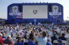 A spectator take a photograph of the stage with both the United States and European teams on it during the Ryder Cup opening ceremony at the Marco Simone Golf Club in Guidonia Montecelio, Italy, Thursday, Sept. 28, 2023. The Ryder Cup starts Sept. 29, at the Marco Simone Golf Club. (AP Photo/Andrew Medichini)