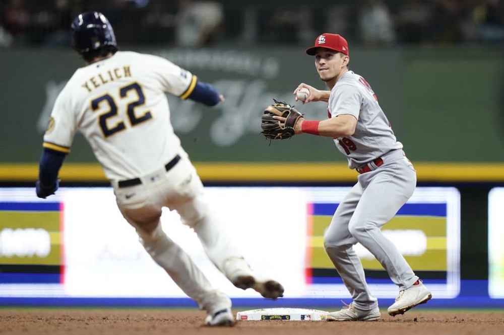 St. Louis Cardinals' Tommy Edman, right, tags Milwaukee Brewers' Christian Yelich (22) out at second base as he throws to first to turn a double play during the fifth inning of a baseball game Thursday, Sept. 28, 2023, in Milwaukee. (AP Photo/Aaron Gash)