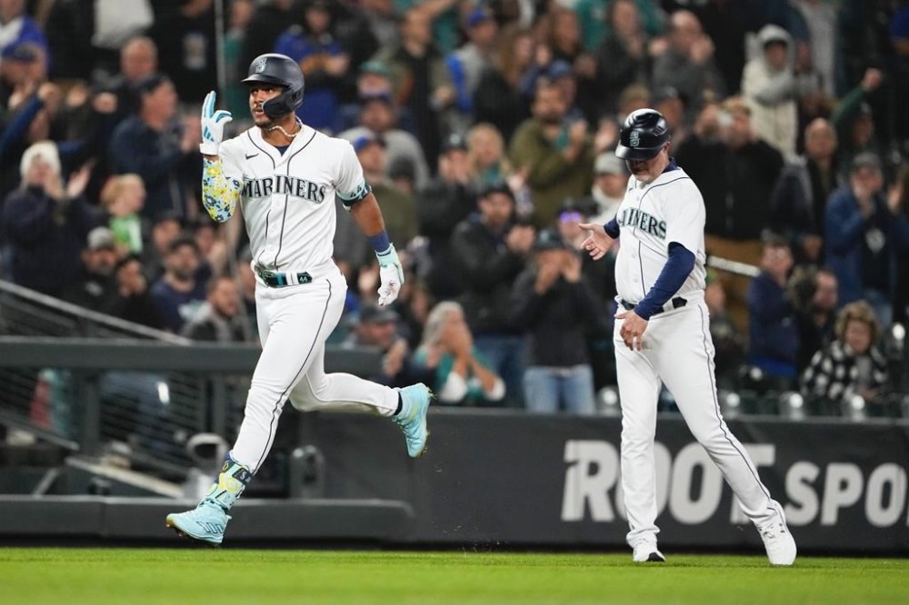 Seattle Mariners' Julio Rodríguez, left, gestures as he runs past third base coach Manny Acta after hitting a solo home run against the Texas Rangers during the fourth inning of a baseball game Thursday, Sept. 28, 2023, in Seattle. (AP Photo/Lindsey Wasson)