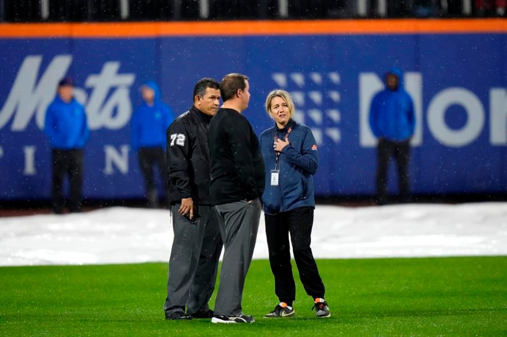 Officials stand on the field after grounds crew members pulled the tarp off of the infield during a rain delay of a baseball game between the New York Mets and the Miami Marlins early Friday, Sept. 29, 2023, in New York. (AP Photo/Frank Franklin II)