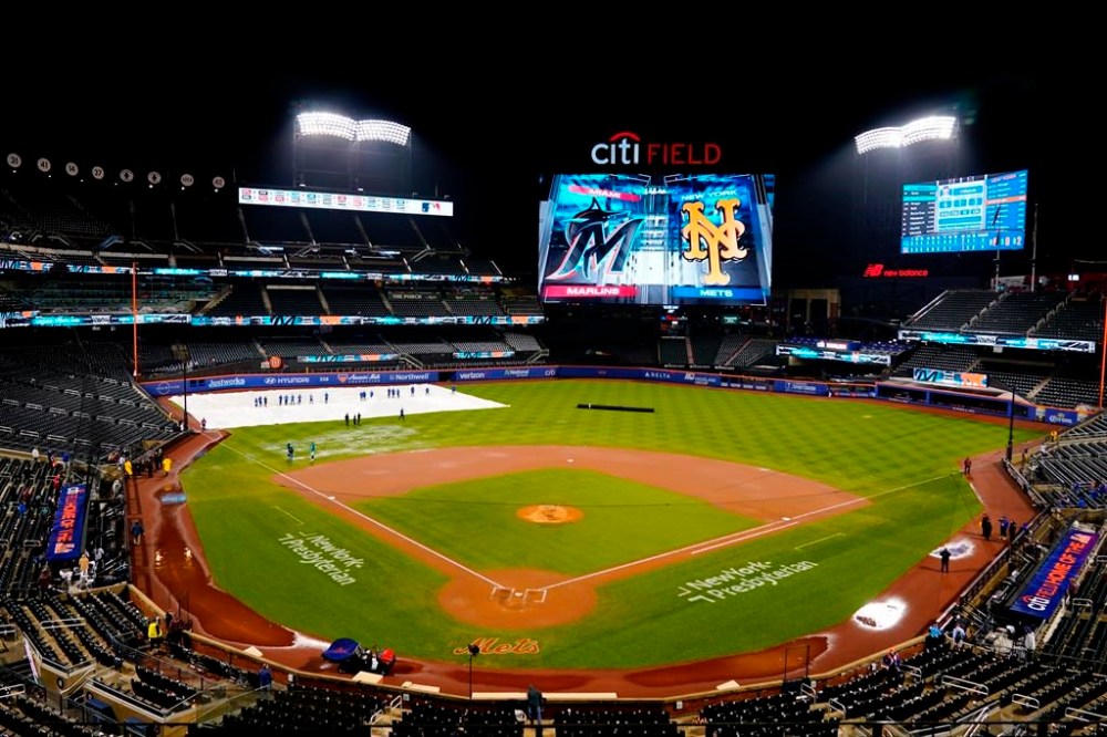 Grounds crew members work on the field during a rain delay in a baseball game between the New York Mets and the Miami Marlins early Friday, Sept. 29, 2023, in New York. (AP Photo/Frank Franklin II)