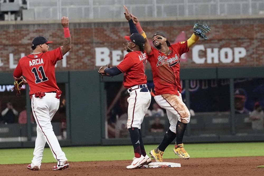 Atlanta Braves from left to right; Orlando Arica (11), Ozie Albies and Ronald Acuna Jr celebrate after defeating the Chicago Cubs in a baseball game, Thursday, Sept. 28, 2023, in Atlanta. (AP Photo/John Bazemore)