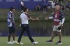 Europe's Rory Mcilroy, centre, goes to shake hands with United States' Patrick Cantlay 's caddie Joe LaCava, on the 18th green following the end of during the afternoon Fourballs matches at the Ryder Cup golf tournament at the Marco Simone Golf Club in Guidonia Montecelio, Italy, Saturday, Sept. 30, 2023. (AP Photo/Alessandra Tarantino)