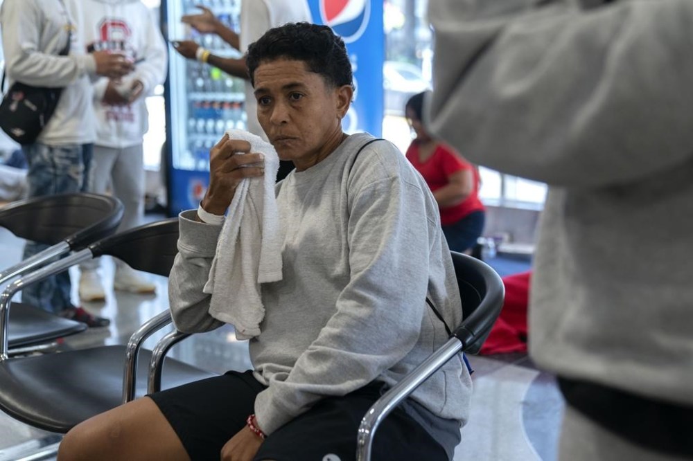 Yoli Cordova, 42, of Venezuela, wipes her face as she sits in a makeshift shelter for migrants at O'Hare International Airport, Wednesday, Sept. 20, 2023, in Chicago. Cordova left her home country because of sexual orientation discrimination and violence against members of the LGBTQ+ community. (AP Photo/Erin Hooley)