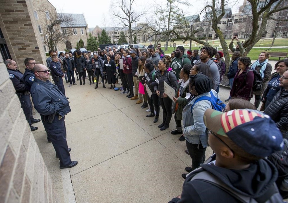 FILE - Police block the entrance into McKenna Hall as Notre Dame students protest an event featuring Charles Murray, a controversial conservative speaker, writer and academic, March 28, 2017, on the campus of the University of Notre Dame in South Bend, Ind. New polling finds that America’s college campuses are seen as far friendlier to liberals than to conservatives when it comes free speech. Polling from the University of Chicago and the AP-NORC Center for Public Affairs Research finds that 47% of adult Americans say liberals are free to express their views on college campuses, while 20% said the same of conservatives. (Robert Franklin/South Bend Tribune via AP)