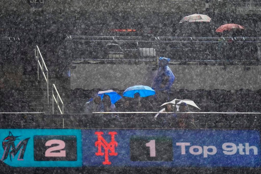 Fans use umbrellas to shield themselves from the rain during a delay in the ninth inning of a baseball game between the New York Mets and the Miami Marlins on Thursday, Sept. 28, 2023, in New York. (AP Photo/Frank Franklin II)