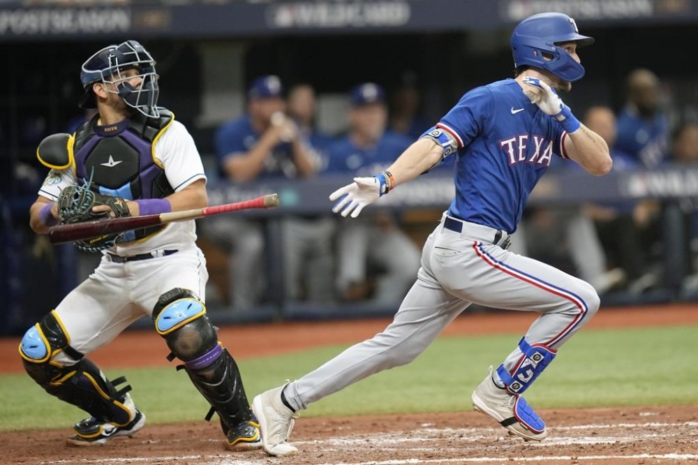Texas Rangers' Evan Carter, right, hits a double in the fourth inning as Tampa Bay Rays catcher Rene Pinto looks on in Game 1 in an AL wild-card baseball playoff series game Tuesday, Oct. 3, 2023, in St. Petersburg, Fla. (AP Photo/John Raoux)