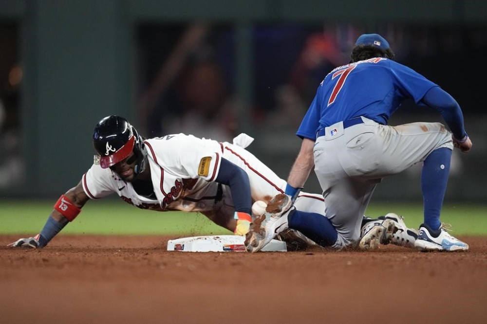 Atlanta Braves' Ronald Acuna Jr. (13) steals second base as the ball gets away from Chicago Cubs shortstop Dansby Swanson (7) in the 10th inning of a baseball game, Wednesday, Sept. 27, 2023, in Atlanta. The stolen base was Acuna's 70th of the season. (AP Photo/John Bazemore)
