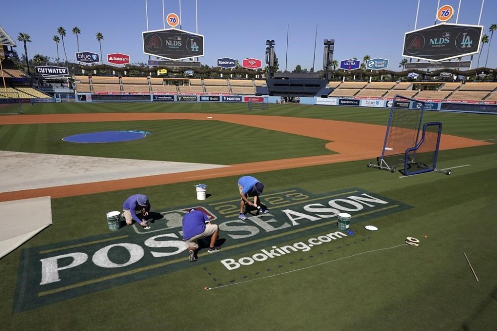 Los Angeles Dodgers grounds crew workers paint the post season logo on the field during practice ahead of the NLDS Friday, Oct. 6, 2023, in Los Angeles. (AP Photo/Mark J. Terrill)