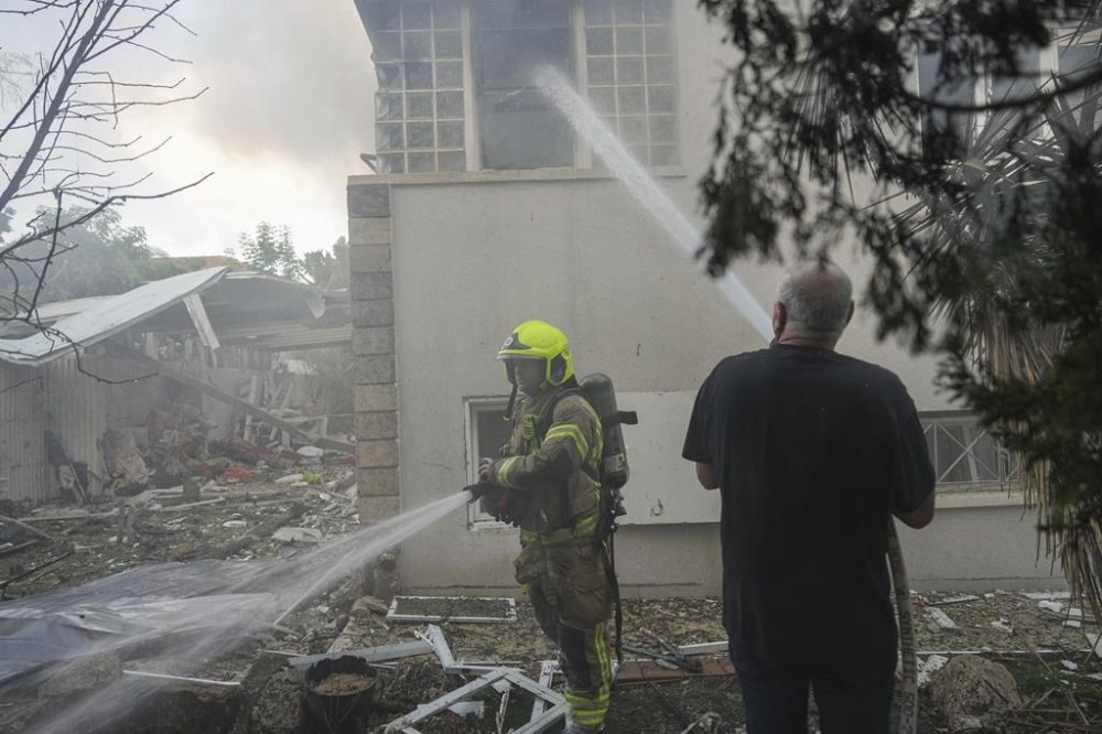 Israeli firefighters extinguish fire after a rocket fired from the Gaza Strip hit a house in Ashkelon, southern Israel, Saturday, Oct. 7, 2023. (AP Photo/Tsafrir Abayov)