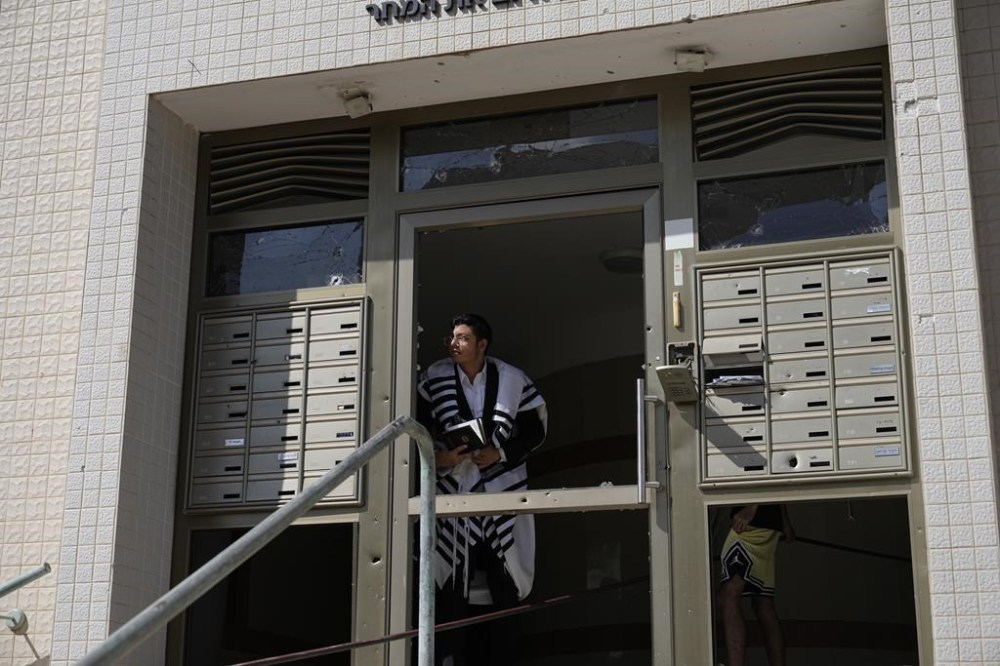 An ultra-Orthodox Jew peers out of a building after a rocket attack from the Gaza Strip in Ashkelon, Israel, on Saturday, Oct. 7, 2023. Palestinian militants in the Gaza Strip infiltrated Saturday into southern Israel and fired thousands of rockets into the country while Israel began striking targets in Gaza in response. (AP Photo/Ohad Zwigenberg)
