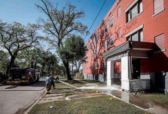 Firefighters wash off the blood on the pavement after a man was found injured outside an apartment block at 285 College Ave. earlier this month. (John Woods / Winnipeg Free Press files)