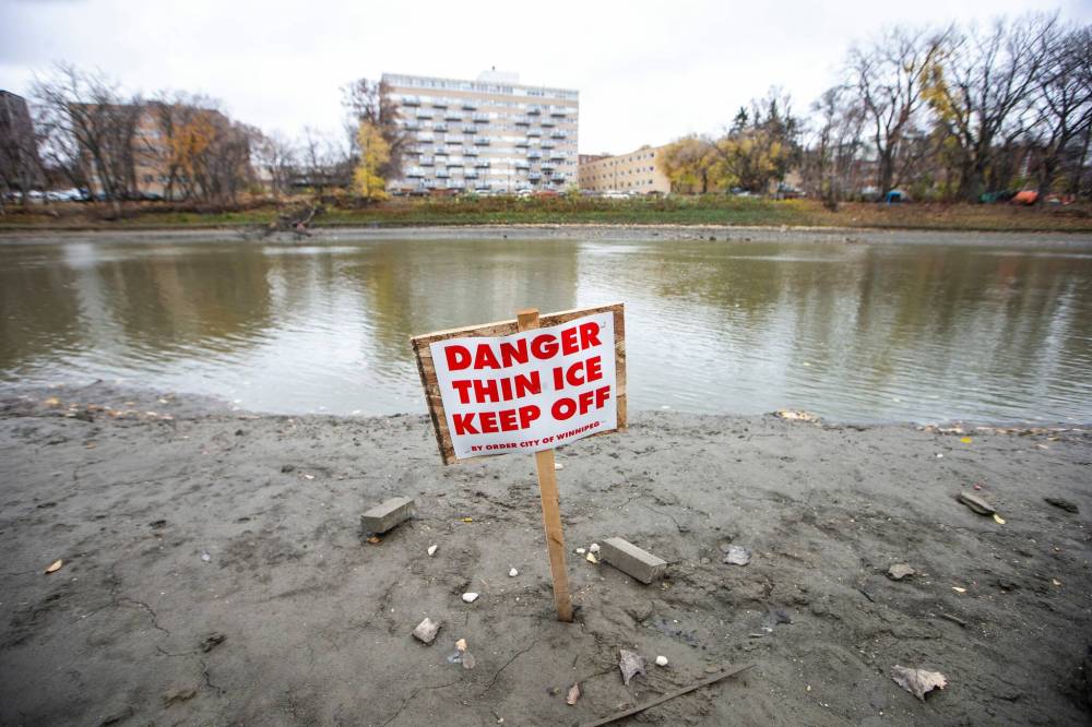 MIKAELA MACKENZIE / WINNIPEG FREE PRESS
Thin ice signs installed along the Assiniboine River near the Legislative Building on Monday. Environment Canada issued a special weather statement that said “confidence is increasing” for southern Manitoba to be hit by snow sometime between mid- to late week.