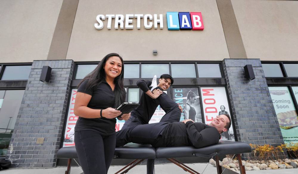 RUTH BONNEVILLE / WINNIPEG FREE PRESS
StretchLab’s general manager Shelly Rabang, with owner, Josh Odwak getting a stretched out by Lead Flexologist, Joseph Yumang, in front of StretchLab’s Winnipeg location on Sterling Lyon Parkway which is still under renovation but will be open in November.
