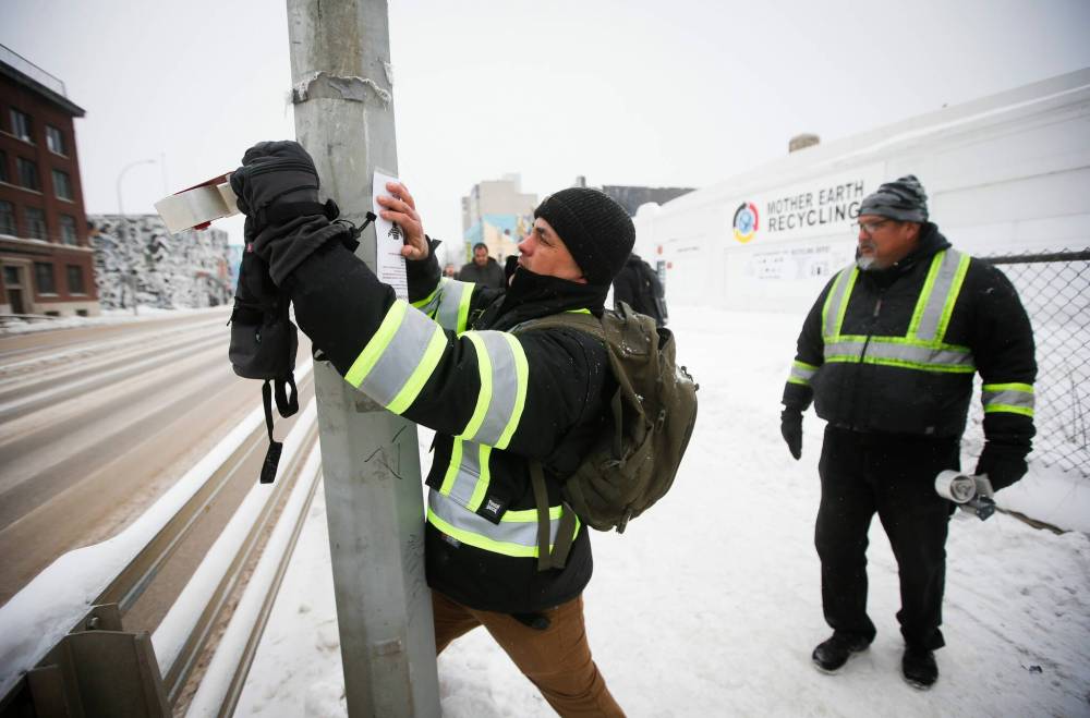 JOHN WOODS / WINNIPEG FREE PRESS
George Robinson, left, and Darryl Contois put up posters on Main Street near Higgins Sunday to help identify Buffalo Woman, an unidentified person who police have said was a victim of an alleged serial killer.