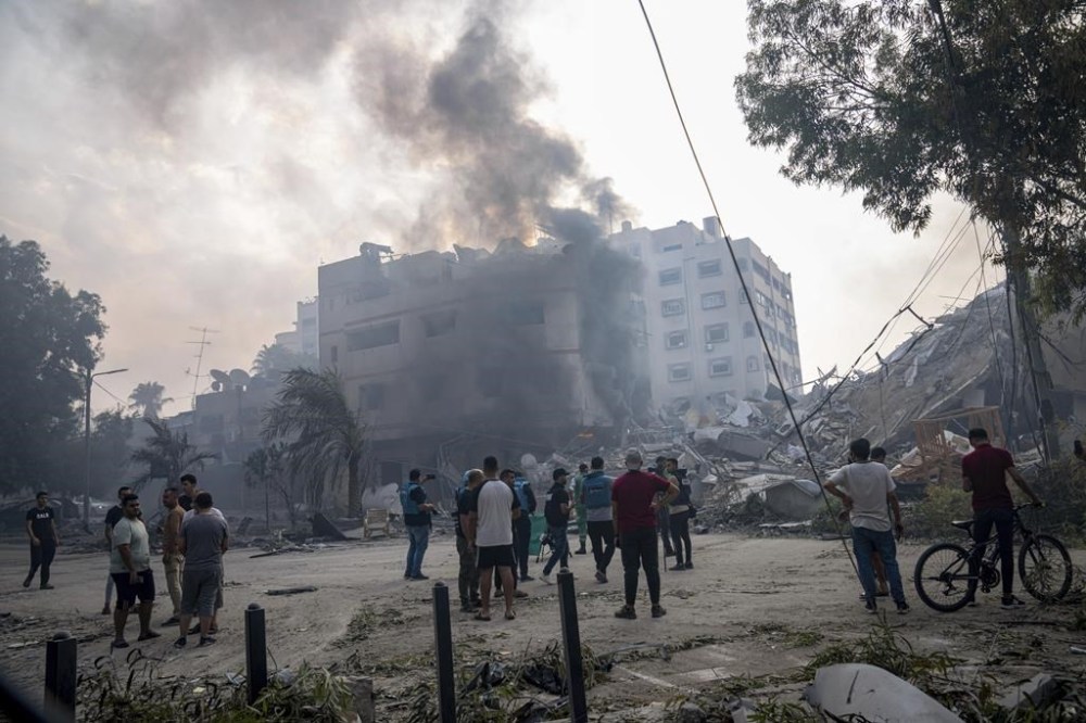 Palestinians inspect the rubble of a building after it was struck by an Israeli airstrike, in Gaza City, Sunday, Oct. 8, 2023. The militant Hamas rulers of the Gaza Strip carried out an unprecedented, multi-front attack on Israel at daybreak Saturday, firing thousands of rockets as dozens of Hamas fighters infiltrated the heavily fortified border in several locations by air, land, and sea, killing hundreds and taking captives. Palestinian health officials reported scores of deaths from Israeli airstrikes in Gaza. (AP Photo/Fatima Shbair)