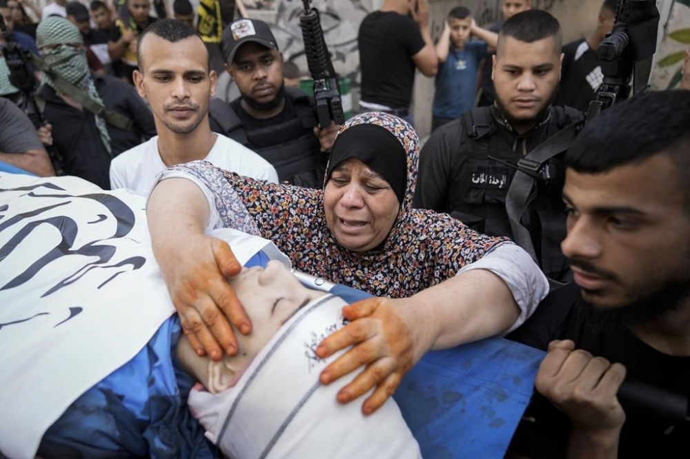 Palestinian relatives mourn over the body of Ahmad Awawda, 19, who was killed in clashes with Israeli troops near the city of Nablus the previous day, during his funeral in the West Bank city of Jenin, Sunday, Oct. 8, 2023. (AP Photo/Majdi Mohammed)