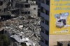 A Palestinian inspects the rubble of a high rise building destroyed by Israeli airstrikes in Gaza City early Sunday, Oct. 8, 2023. Israeli soldiers are battling Hamas fighters in the streets of southern Israel and launching airstrikes on Gaza a day after an unprecedented surprise attack by Hamas fighters. (AP Photo/Adel Hana)