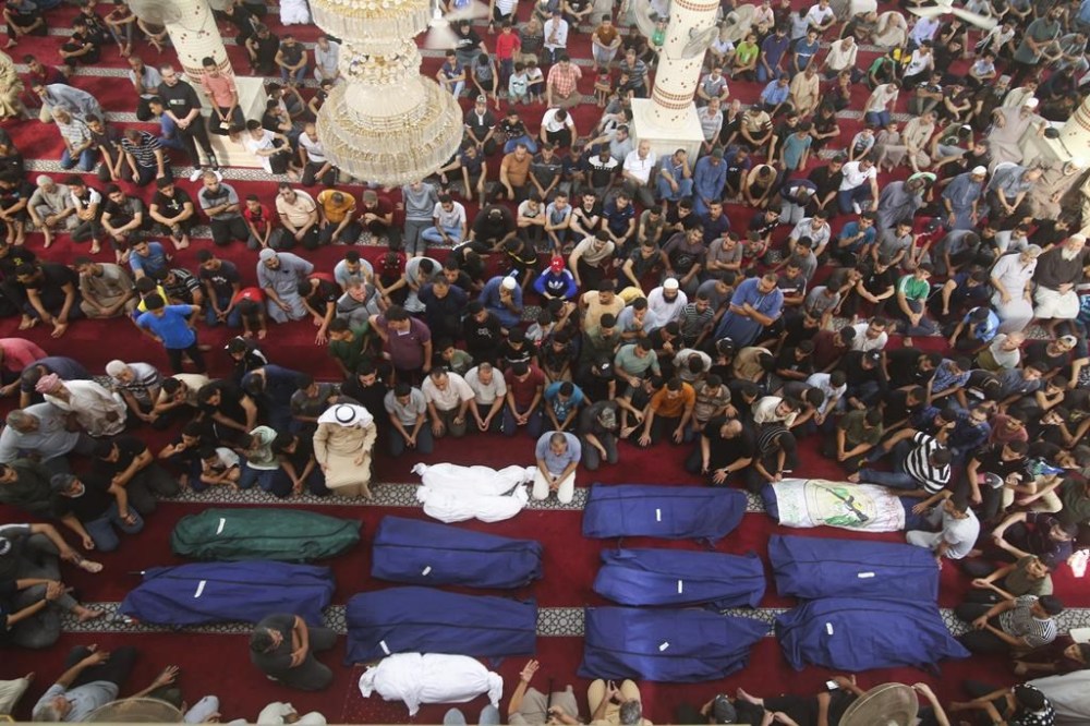 Mourners pray by the bodies of Salem Abu Quta family members, a Hamas fighter, during a funeral after they were killed in an Israeli strike on their house in Rafah refugee camp, southern Gaza Strip, Sunday, Oct. 8, 2023. (AP Photo/Hatem Ali)