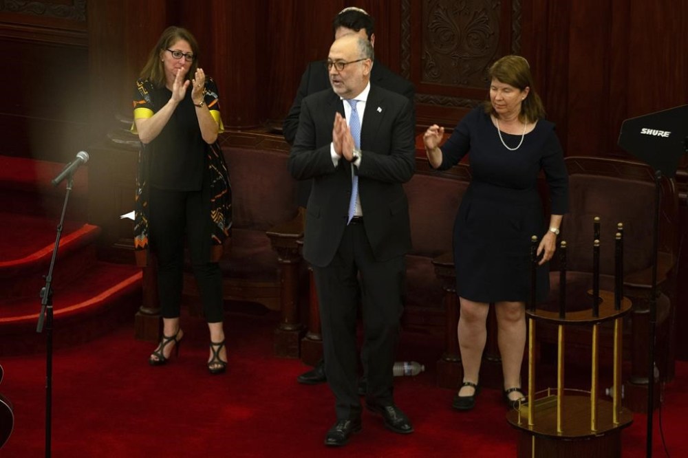 Israeli Ambassador Marco Sermoneta, second from right, reacts to applause from the audience during