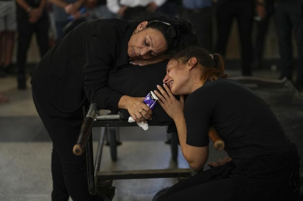 Mourners react beside the body of Mapal Adam, during her funeral in Tel Aviv, Israel, Wednesday, Oct. 11, 2023. Adam was killed by Hamas militants on Saturday as they carried out an unprecedented, multi-front attack that killed over 1,000 Israelis. (AP Photo/Francisco Seco)