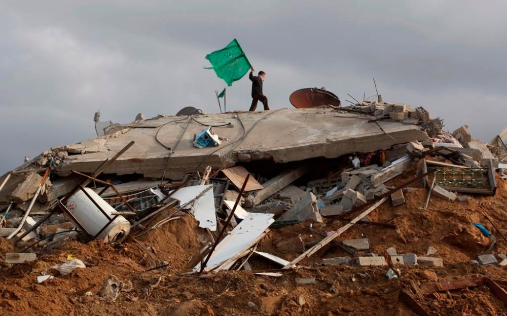 FILE - A Palestinian boy holds a Hamas flag over a destroyed house in Beit Lahia, northern Gaza Strip, Monday, Jan. 19, 2009. The Hamas militant group has issued its first statement, Monday, on losses suffered during Israel's latest offensive in the Gaza Strip, stating that the group lost 48 fighters, and the Health Ministry says more than 1,200 Palestinians died in the fighting. (AP Photo/Hatem Moussa, File)