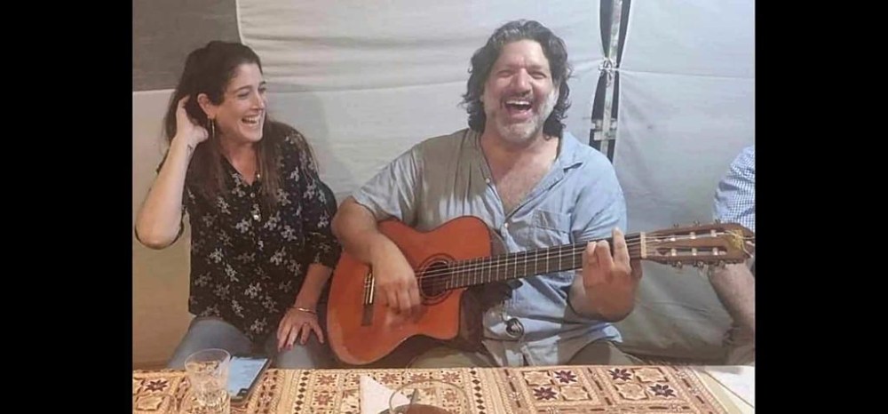 This image provided by Eran Shani shows Shlomi Mathias playing the guitar as his wife, Debbie ‘Shahar’ Mathias, laughs and sings next to him at her 50th birthday party on Oct. 1, 2023, in Lehavim, Israel. They both died days later while protecting their 16-year-old son, Rotem Mathias, from Hamas fighters who attacked their kibbutz in Israel near the border with Gaza on Oct. 7, 2023. (Eran Shani via AP)