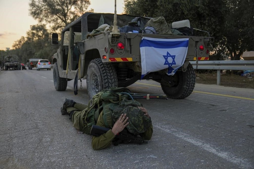An Israeli soldier mistakenly thinks he hears an air raid siren and jumps to the ground to take cover in Kibbutz Be'eri, Israel, Wednesday, Oct. 11, 2023. The kibbutz was overrun by Hamas militants from Neraby Gaza Strip Saturday when they killed and captured many Israelis. (AP Photo/Ohad Zwigenberg)