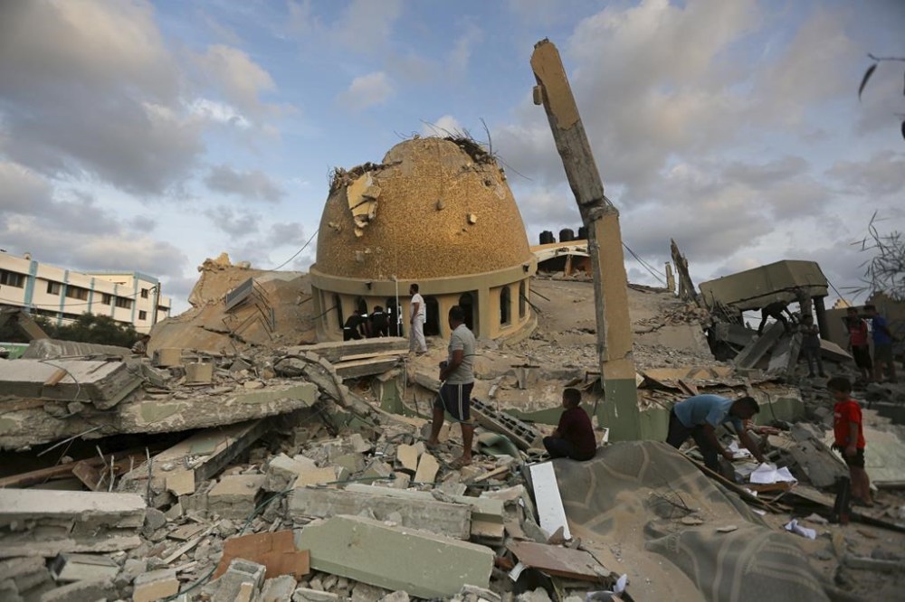 FILE - People stand outside a mosque destroyed in an Israeli air strike in Khan Younis, Gaza Strip, Sunday, Oct.8, 2023. As Israeli warplanes pummel Gaza to avenge the Hamas attack, Palestinians say the military has largely unleashed its fury on civilians. (AP Photo/Yousef Masoud, File)